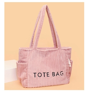 Makroansicht der rosa Cord-Stoffstruktur und TOTE BAG Bestickung auf der Tasche