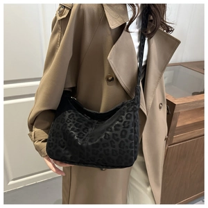 Dettaglio della borsa hobo leopardata nera con tracolla indossata da una modella in trench