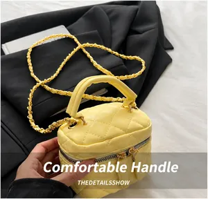 Détail du mini sac jaune matelassé avec bandoulière chaîne sur un blazer noir chic
