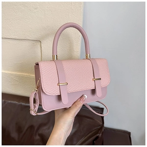 Détail du rabat tissé rose et des ferrures dorées sur le sac à main tendance pour femmes