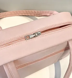 Gros plan de la fermeture éclair en métal et des anses du sac cabas en toile rose