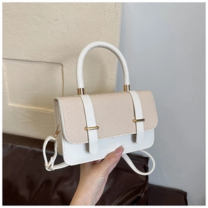 Détail du sac à main en paille tressée et cuir blanc avec boucles métalliques dorées