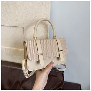 Détail d'un sac à main beige avec texture tissée et détails métalliques dorés fins