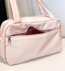 Détail du sac cabas en nylon rose montrant la poche zippée avant avec un grand portefeuille