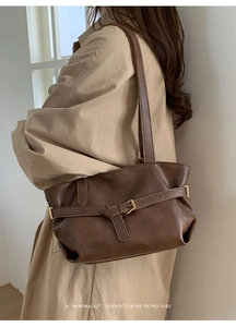 Detail of retro brown leather tote bag with metal buckle strap and elegant pleats