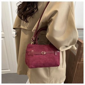 Vue détaillée du sac seau bordeaux en daim mat avec des boucles élégantes en métal doré