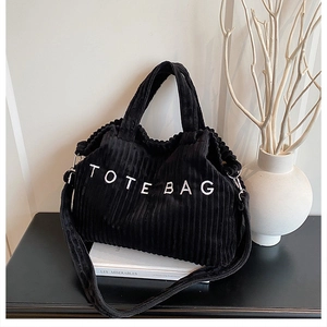 Détail du cabas en velours côtelé noir montrant la texture et la broderie TOTE BAG