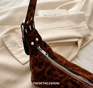 Détail de la fermeture éclair en métal et de la boucle sur un sac à bandoulière léopard