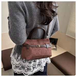 Detail showing vintage suede bucket bag with leather strap and golden buckle accent