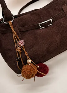 Detail of dark brown suede tote bag featuring bohemian charms and vintage metal buckle