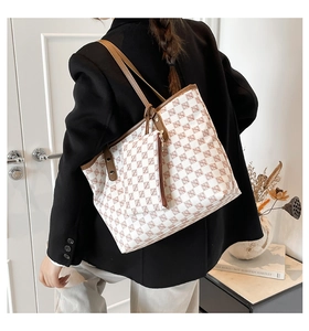 Detail view of white monogram tote bag with brown leather straps and matching pouch