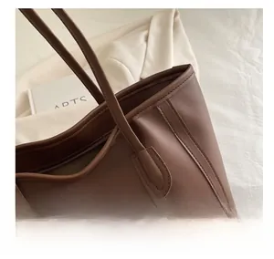 Macro shot of warm brown tote bag showing premium leather texture and stitching