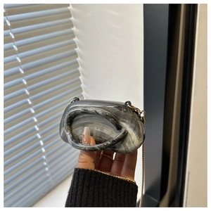 Dettaglio della mini borsa in acrilico effetto marmo con catena dorata e manico