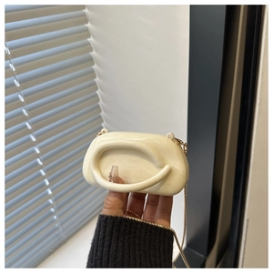 Dettaglio della borsa clutch in acrilico crema marmorizzato con catena dorata