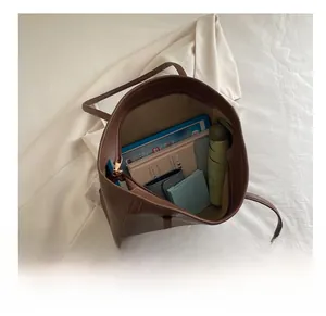 Detail view of large dark brown leather tote bag interior holding a tablet and umbrella