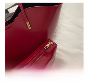 Detail of red glossy tote bag with smooth gold zipper and matching inner pouch