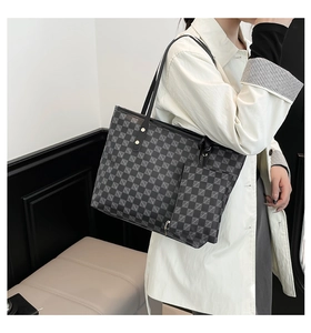 Detalle de un bolso tote con monograma a cuadros y un monedero a juego con cremallera