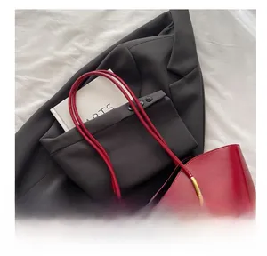 Detail of red oil wax leather tote bag with thin handles and gold hardware connectors