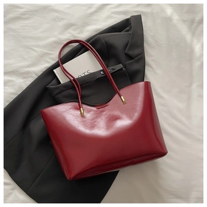 Detailed top view of a dark red tote bag featuring gold hardware on white fabric