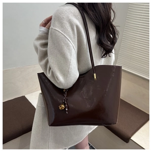 Close-up of a large dark brown oil-wax leather tote bag with stylish metallic charms