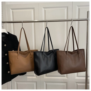 Close-up of minimalist leather tote bags in light brown, black, and dark brown colors