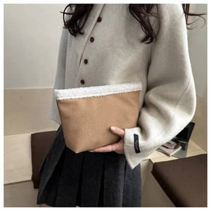 Close-up of khaki faux leather clutch featuring white faux shearling trim details