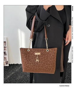 Detail of leopard print tote bag with gold deer charm and chain strap on black coat