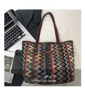 Detail of woven tote bag with zigzag patterns and brown leather handles in office setting