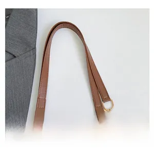 Dettaglio del manico in ecopelle marrone con catena in metallo dorato su una borsa