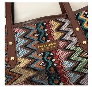 Close-up of woven zigzag tote with brown leather handles and golden rivet accents