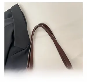 Close-up of a wide brown leather shoulder strap with detailed stitching for a crossbody bag