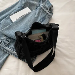Détail de l'intérieur spacieux d'un sac léopard contenant téléphone, portefeuilles et rouge