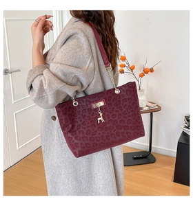 Detail of burgundy leopard tote bag featuring gold deer charm and chain leather strap