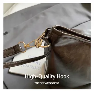 Détail de la texture en cuir marron foncé et du crochet en métal doré du sac à main