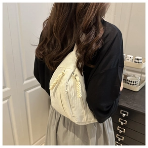 Detailed view of cream corduroy crossbody bag with woven zipper pull on model
