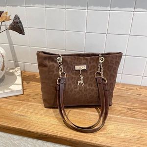 Retro leopard print tote bag with gold chain strap and elk charm on a wooden surface