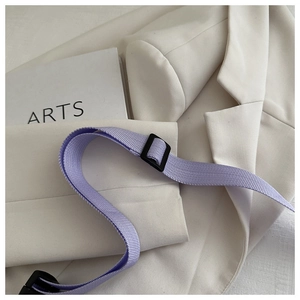 Macro shot of an adjustable purple corduroy crossbody strap with a black plastic buckle