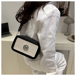 Detailaufnahme der schwarz-weißen Umhängetasche mit breitem Gurt und metallischem M-Logo