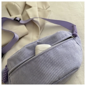 Macro shot of a purple corduroy sling bag showing interior space with earphone case