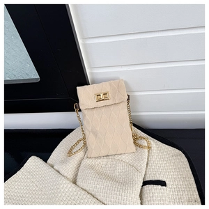 Detail of beige textured plush bag featuring gold metal clasp and elegant chain strap