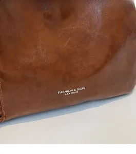 Détail d'un sac cabas en cuir marron foncé avec coutures fines et logo gravé