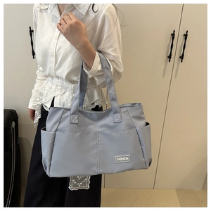 Close-up of the large nylon tote bag showing side pockets and a fashion label detail