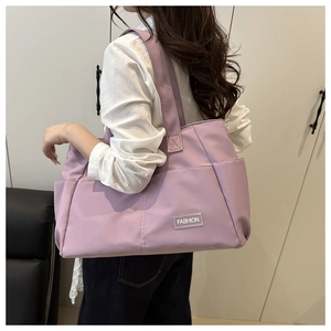 Detail view of large purple nylon tote bag featuring a Fashion label and side pockets