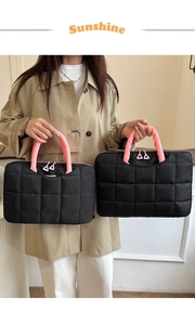 Vue détaillée du sac d'ordinateur matelassé noir avec poignées roses et zips roses