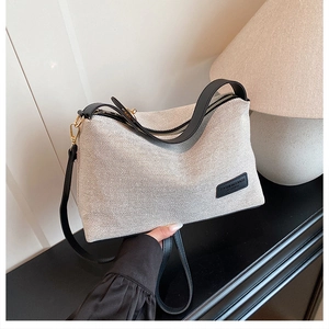 Detail of canvas tote bag featuring premium leather handle and fashion logo plaque