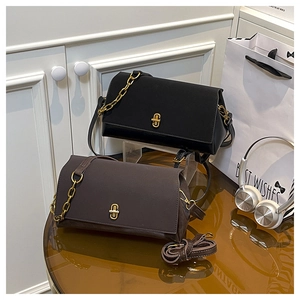 Détail de sacs bandoulière en daim avec boucle dorée en H et chaînes en noir et marron foncé