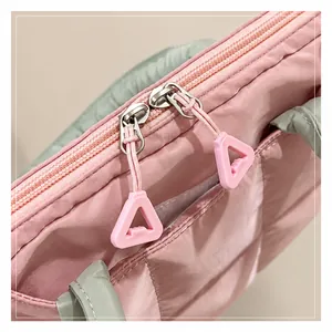 Gros plan d'un sac matelassé rose montrant des fermetures éclair et tirettes en résine