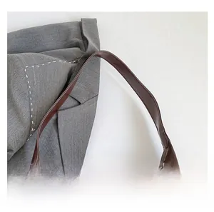 Detail shot of the reinforced brown leather handle and stitching of this tote bag
