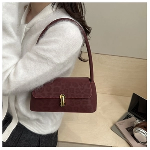 Detail of burgundy leopard print baguette bag with gold buckle on a shoulder strap