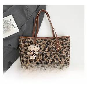 Leopard print tote bag detail with brown leather handles and cute cat plush charm